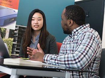 Two students talking at a desk