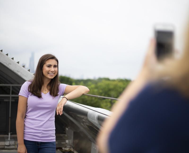 A student has her parent take her picture on the roof of SSV