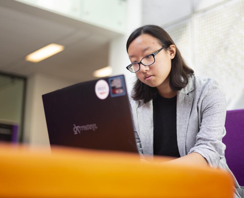 Anna Kong does data work on her laptop in the Retaliatta Atrium